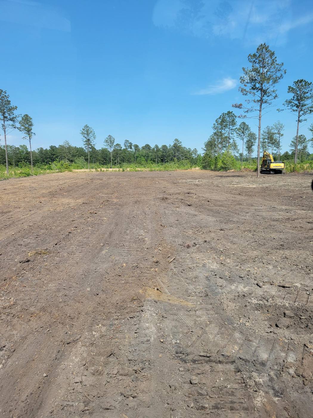 Large cleared lot with excavator in the background