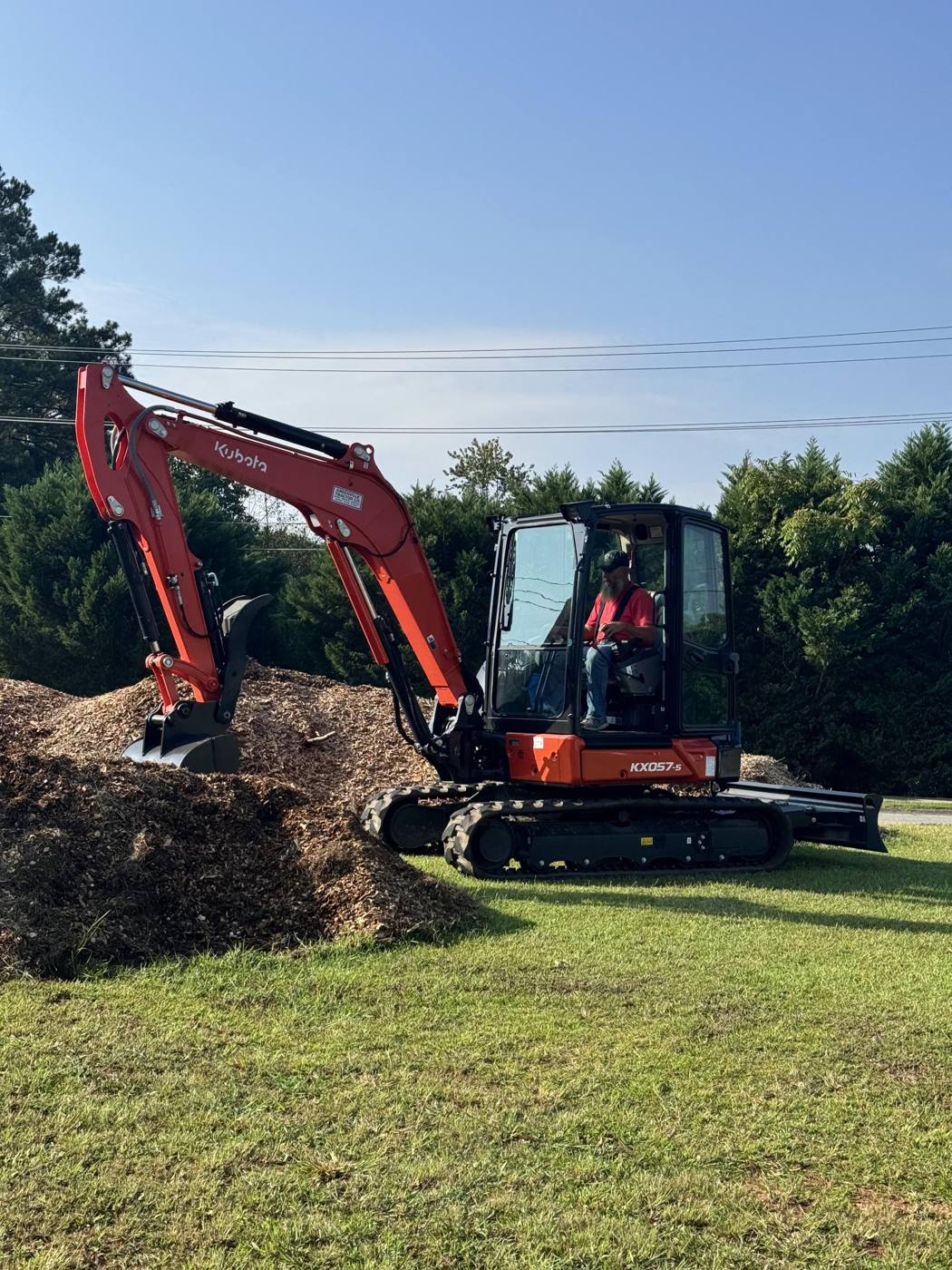 Estley Services mini excavator working a pile of wood chip mulch
